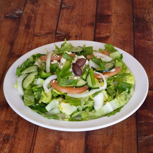 Fresh Greek salad with lettuce, tomatoes, cucumbers, onions, bell peppers, feta, and olives.